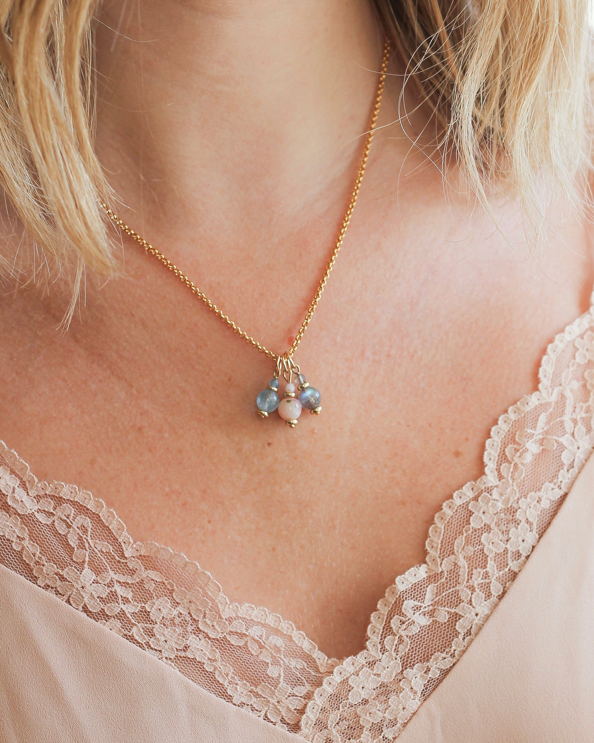 gemstone charm layered with other meaningful charms on a gold necklace.