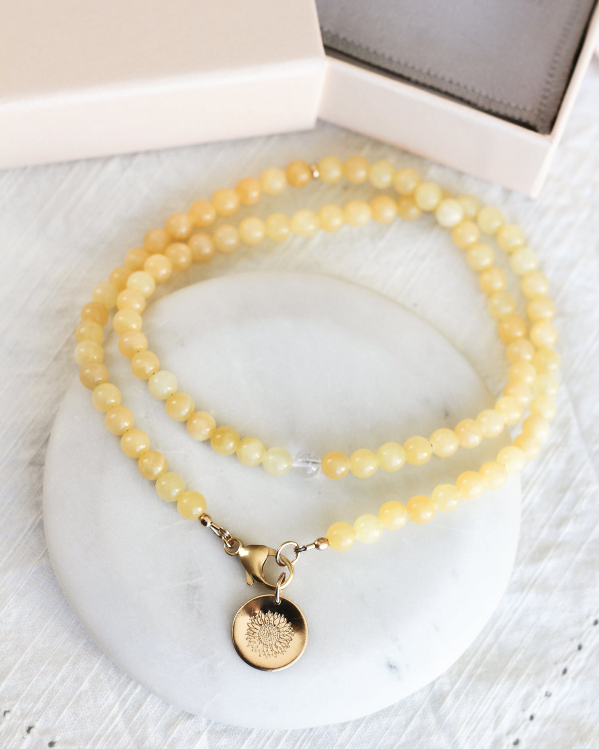 Close-up of round 6mm Honey Calcite gemstone beads in warm golden yellow tones with gift box