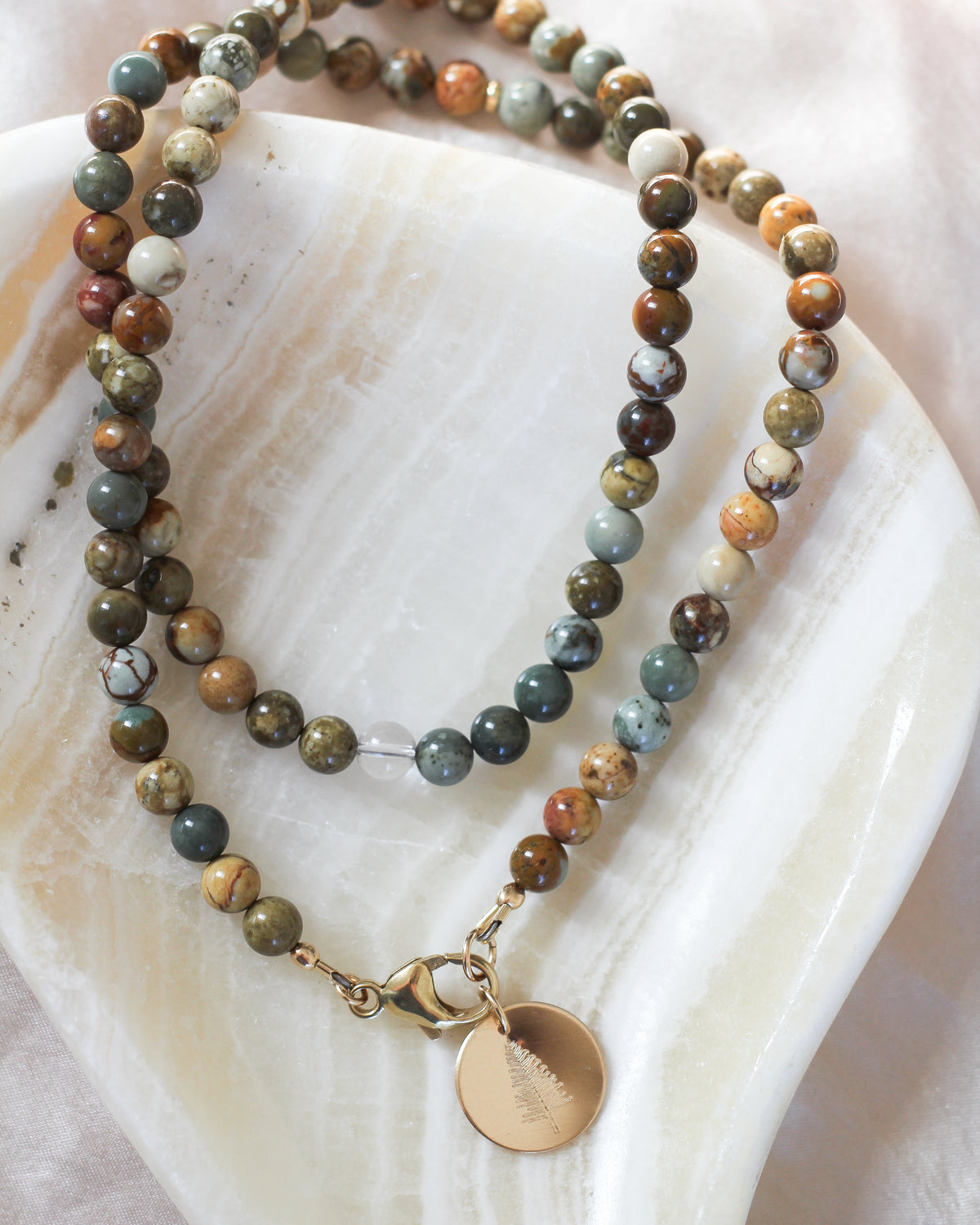 Close-up of smooth, round 6mm Jasper gemstone beads with natural earthy patterns.