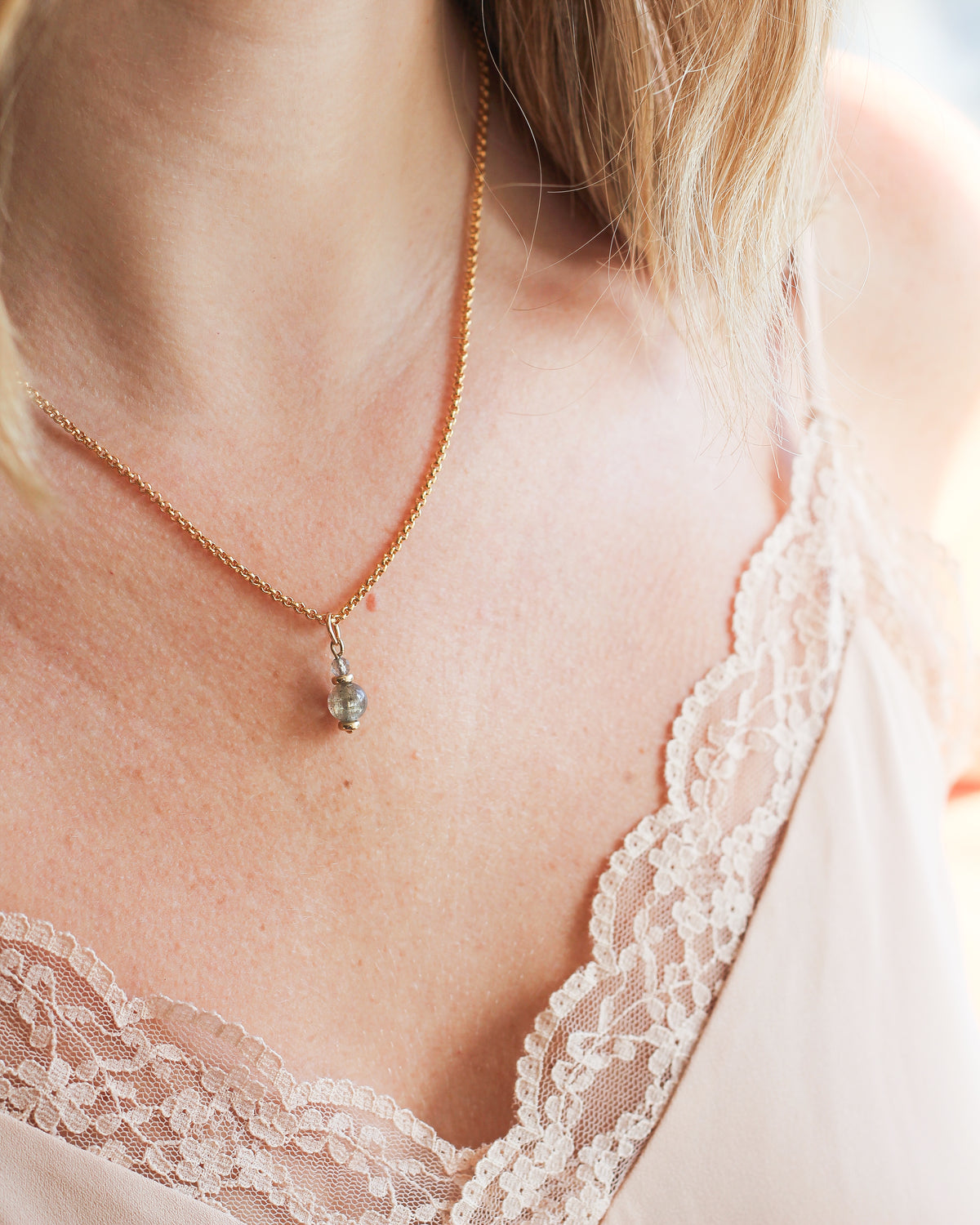 Labradorite gemstone charm styled on a delicate gold necklace.