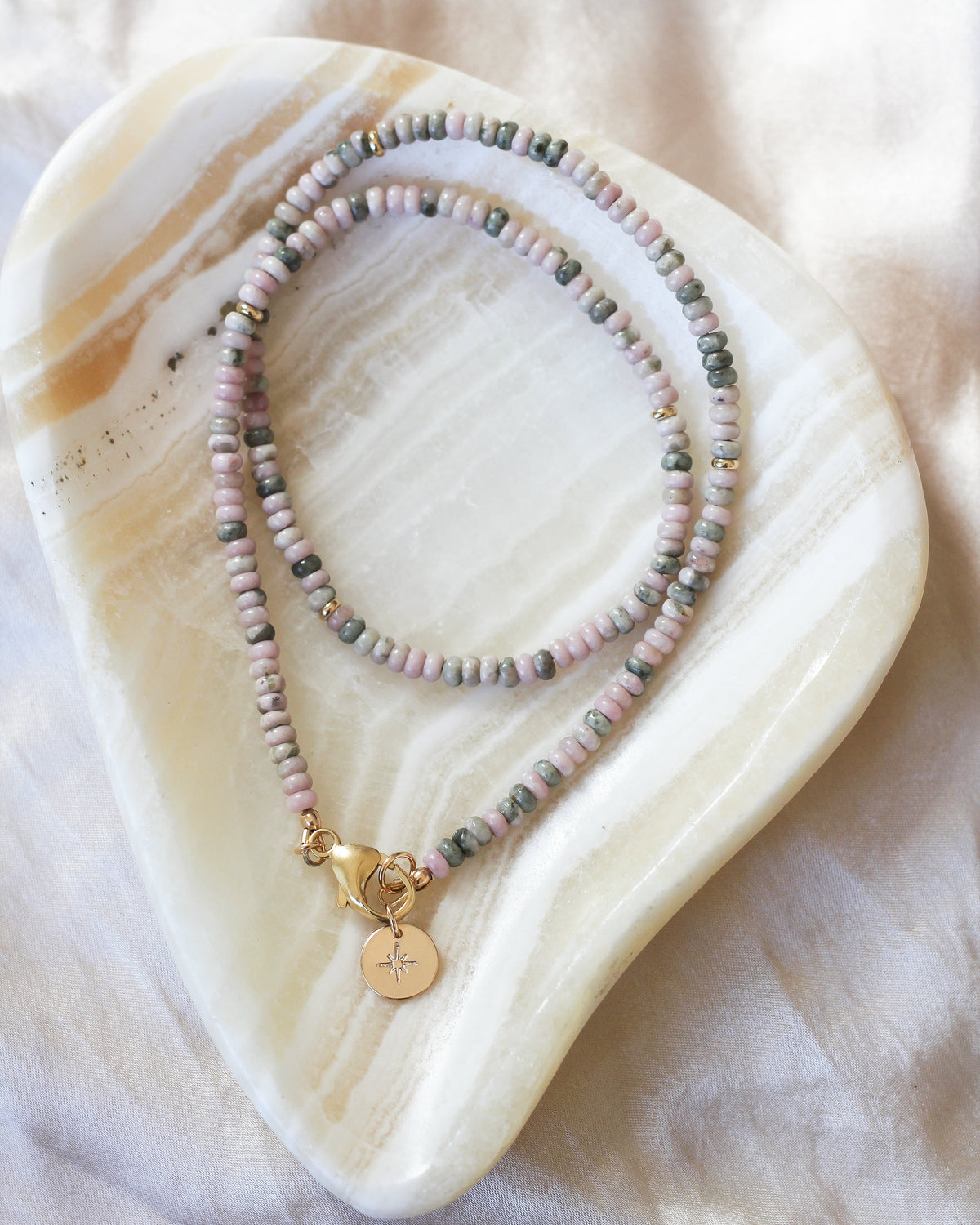Close-up of 4mm rondelle Nevada Lapis gemstone beads in soft pink and earthy green hues.