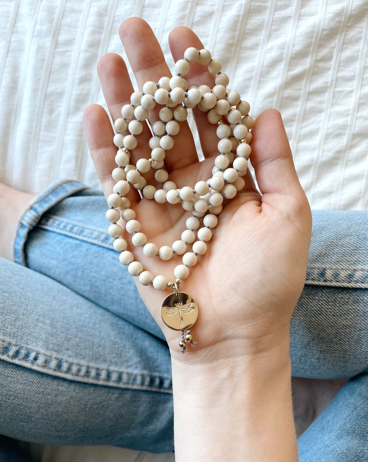 riverstone mala pendant necklace with dragonfly medallion in hand