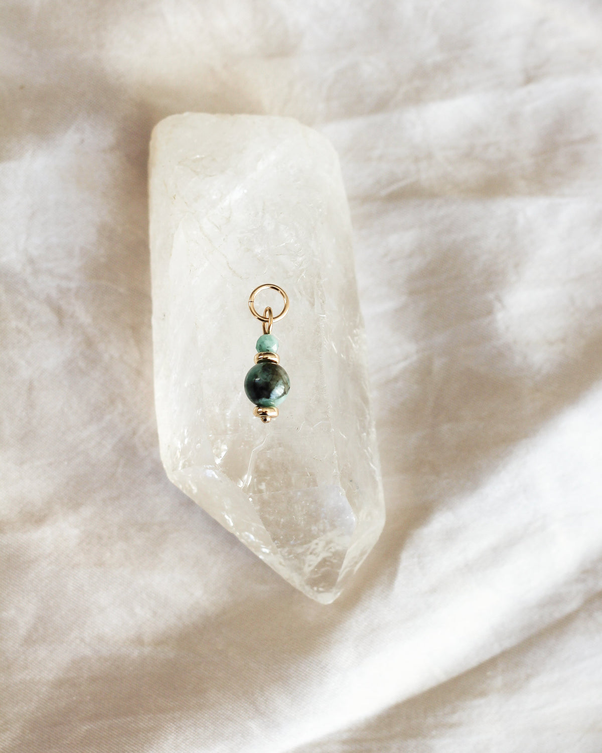 Close-up of green Emerald gemstone beads on a handmade necklace charm.