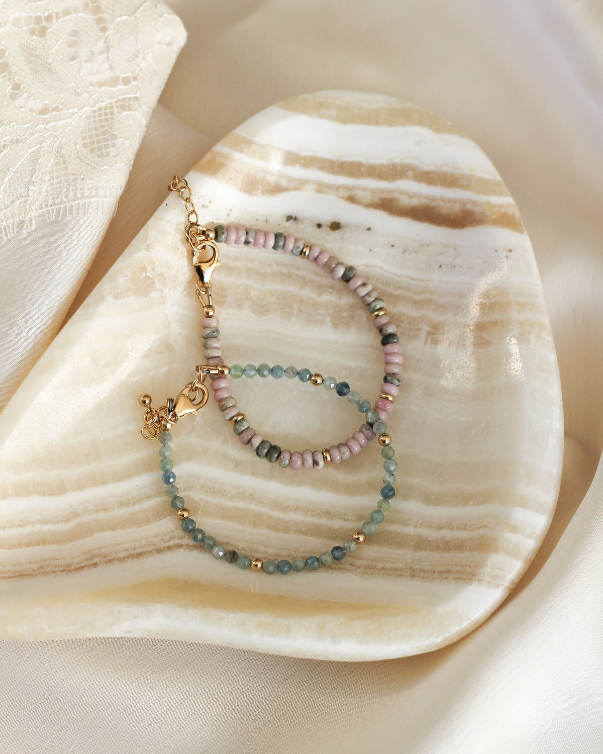 Close-up of faceted Nevada Lapis gemstone beads in soft pink and earthy green hues.