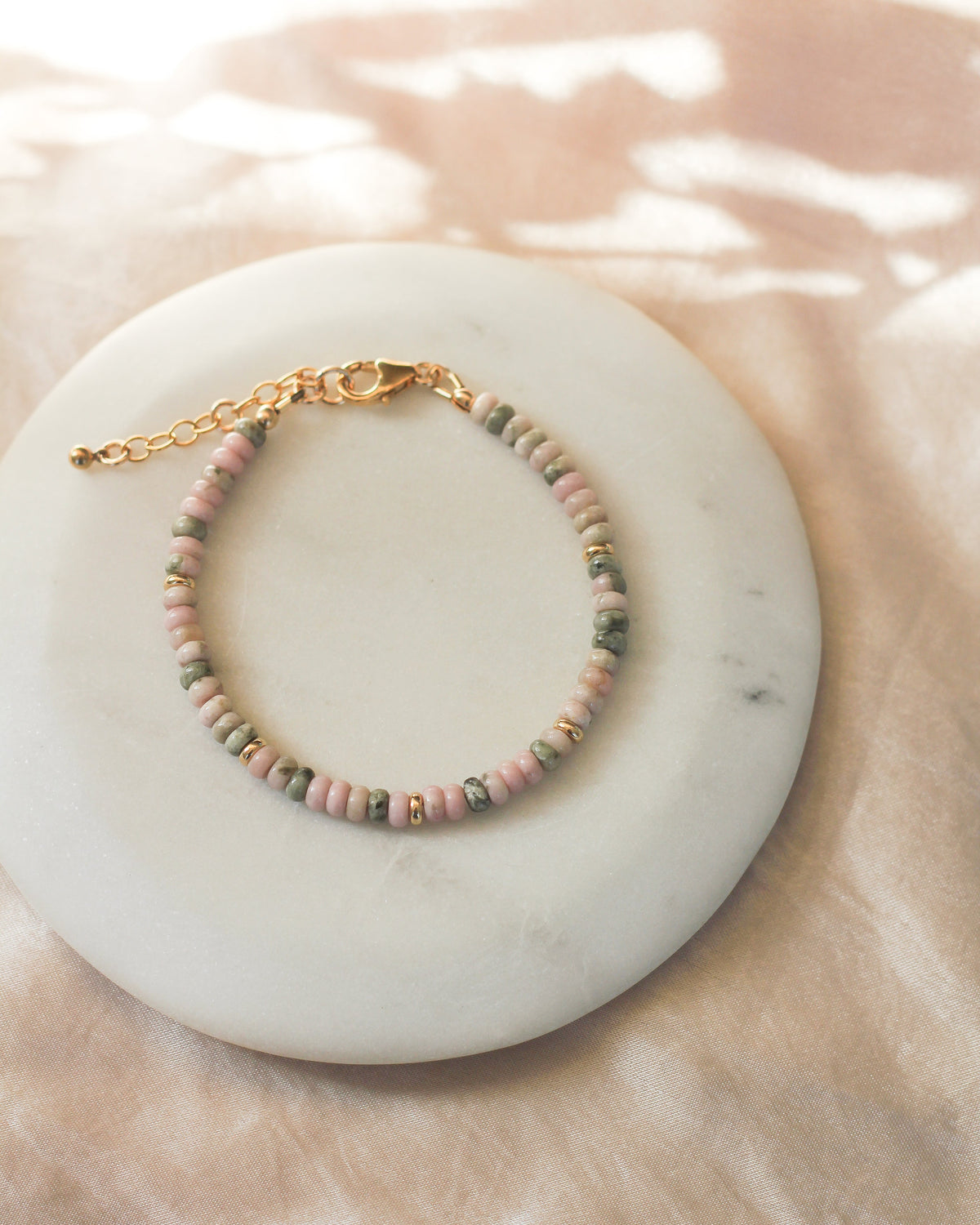 Close-up of faceted Nevada Lapis gemstone beads in soft pink and earthy green hues.